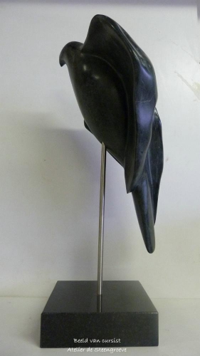 Een beeld van Zwart Indiaas speksteen op een zwart granieten sokkel